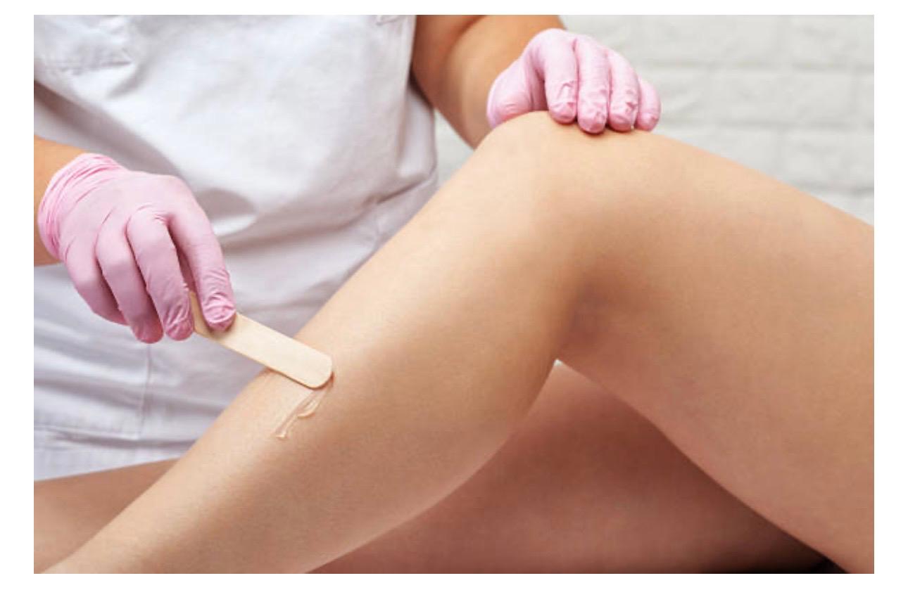 Warm salon waxing treatment room with soft towels and skincare products.